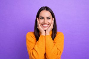 A smiling young woman with white teeth on a purple background, showcasing natural results of how to get white teeth