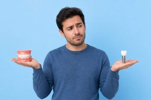 An image of a man thinking about dental implants vs. dentures